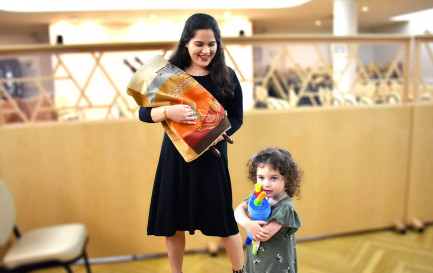 Une femme juive orthodoxe tient un rouleau de la Torah tandis que sa fille embrasse un jouet de la Torah. / RNS